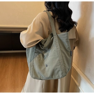 Detail shot of a grey-green canvas tote bag with front pocket and shoulder strap style