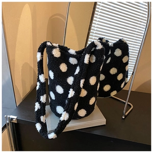 Detailed view of the soft black plush bucket bag featuring classic white polka dots and wide strap