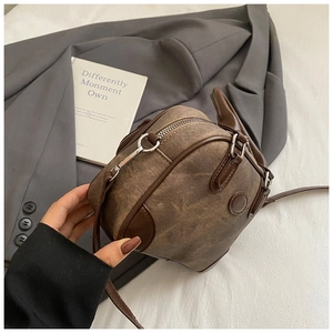 Detailed close-up of brown canvas and leather trim bag held by a hand for size scale