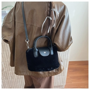 Close-up of black fuzzy plush bucket bag with leather handle and silver metal buckle