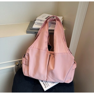 Gros plan d'un sac cabas rose montrant des poches latérales et le détail du tissu nylon