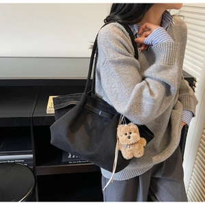 Detail of vintage black tote bag with pleated sides and cute brown bear pendant charm
