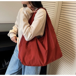 Détail d'un grand sac à bandoulière bordeaux minimaliste montrant le tissu en nylon