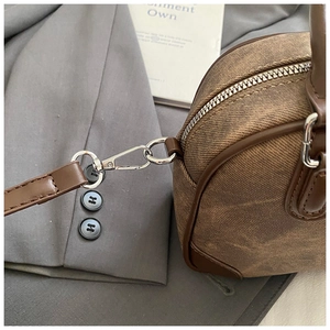 Close-up of silver hardware lobster clasp and D-ring on a retro brown pillow bag