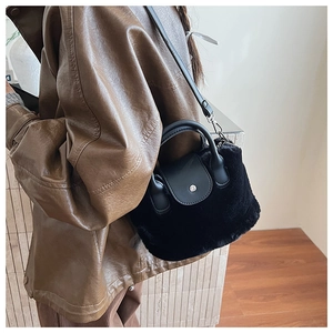 Detailed view of black faux fur bucket bag with matte leather handle and metal hardware