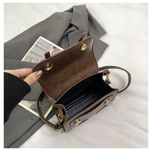 Detailed view of the brown retro crossbody bag featuring dual golden magnetic buckles