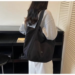 Detailed view of black lightweight nylon tote bag with wide straps and CM circular logo