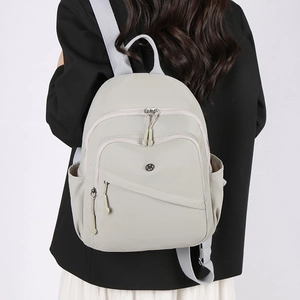 Lightweight beige nylon backpack for women with multi-pocket design on model