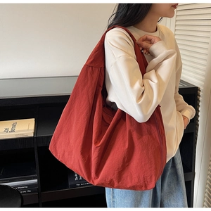 Détail d'un grand sac hobo en nylon rouge brique avec bandoulière large pour le quotidien