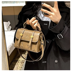 Detail of vintage brown leather handbag with star patches and golden studs on the flap