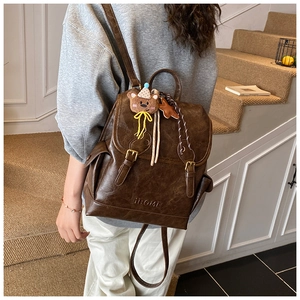 Brown vintage faux leather backpack with a cute bear charm shown on a model's back