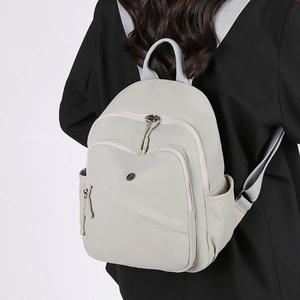 Close-up of lightweight nylon backpack showing multiple zipper pockets and side pouch