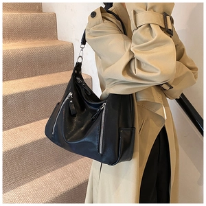Close-up of black leather tote bag with silver zippers shown on a model