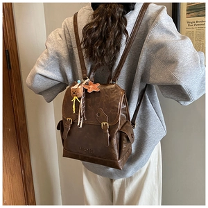 Detail view of vintage brown leather backpack with belt buckles and FEIYU embossed logo