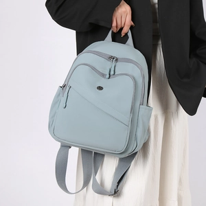 Close-up of light blue nylon backpack with functional zippers and metallic logo detail