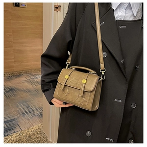 Close-up of khaki retro crossbody bag with star patches on model wearing black wool coat