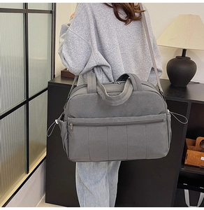 Gray large travel bag with side pockets and adjustable strap shown in home setting