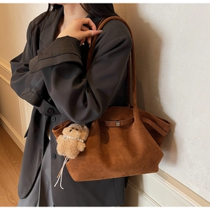 Detail of vintage brown suede tote bag with plush bear pendant and large capacity