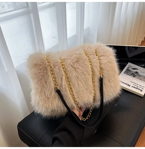 Detail of plush faux fur shoulder bag with gold chain strap and black padded leather grip