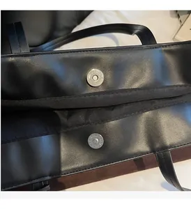 Dettaglio della chiusura magnetica e degli accessori in metallo argentato su borsa nera