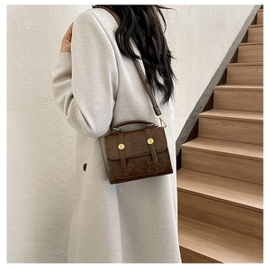 Close-up of retro brown handbag featuring star stitching and gold metal accents