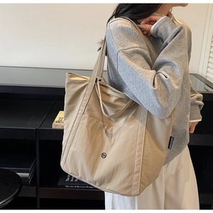 Detail view of khaki large capacity tote bag with front pocket and round metal button