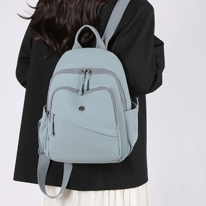 Gray-blue nylon backpack shown on model with multiple functional zipper pockets