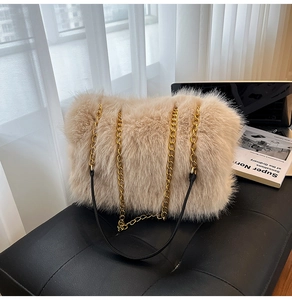 Detail of beige faux fur shoulder bag with gold chain straps on a black bench