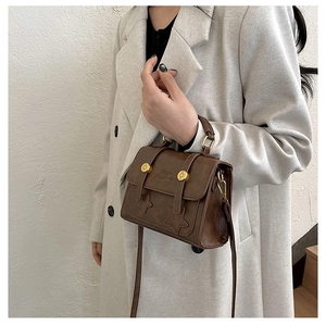Close-up of vintage brown leather crossbody bag with star embossing and gold buckles