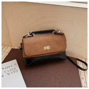 Détail du sac vintage avec rabat en daim marron et cuir matelassé noir avec fermoir doré