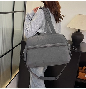 Large dark grey travel bag showing spacious front zipper pocket and adjustable strap
