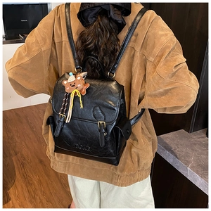 Detailed back view of a retro black faux leather backpack with a knitted bear charm