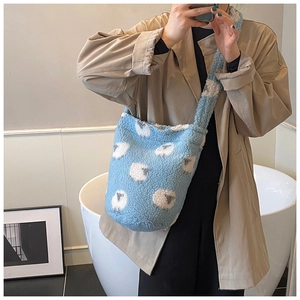 Light blue plush bucket bag with cartoon sheep print worn over a long khaki coat