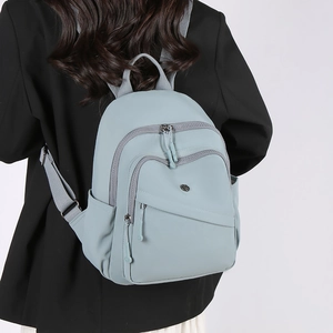 Back view of light blue nylon backpack on black blazer showing sleek design and side pockets