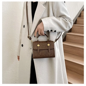 Detail of vintage brown leather crossbody bag with star stitching and gold buckles