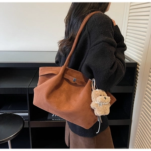Brown vintage tote bag detail with plush puppy pendant and pearl necklace decoration