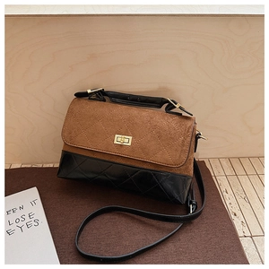 Détail du sac à bandoulière en daim marron et cuir noir avec matelassage et fermoir doré