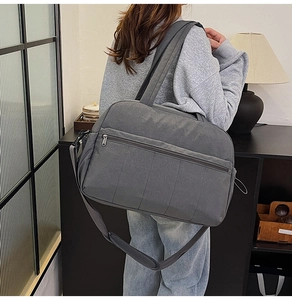 Detail of dark grey travel tote bag with vertical stitching and adjustable strap