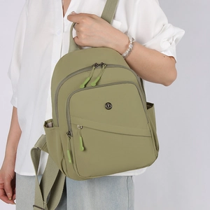 Detail view of the olive green lightweight nylon backpack with a circular metal logo and side pockets