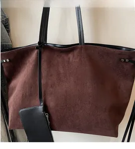 Dettaglio della borsa tote in pelle scamosciata marrone con logo e mini pochette