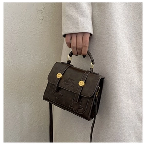 Detail of vintage dark brown crossbody bag featuring star embossing and gold hardware