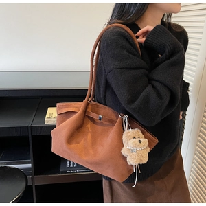 Detail of vintage brown suede tote bag featuring a cute plush teddy bear charm