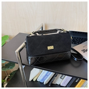 Détail d'un sac à main matelassé noir avec patchwork en daim et fermoir rotatif doré