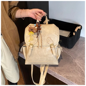 Detail of beige textured leather backpack featuring BOME embossing and buckle closure
