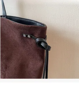 Dettaglio borsa tote in pelle scamosciata marrone con finiture in pelle nera e borchie