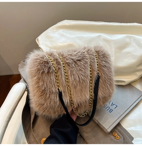 Detail of plush brown faux fur shoulder bag with gold metal chain strap on chair