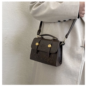 Close-up of deep brown leather mini bag with stitched stars and vintage gold hardware