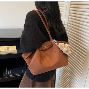 Detail of vintage brown suede bucket bag with leather strap and plush bear charm decoration