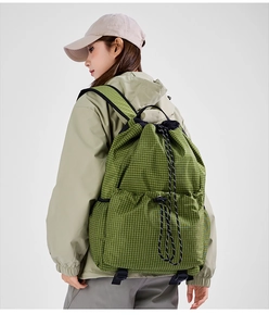 Close-up of green checkered drawstring backpack on model showing large capacity and mesh pocket