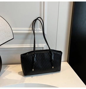 Gros plan d'un sac à bandoulière noir plissé avec détails en métal doré et nœuds élégants